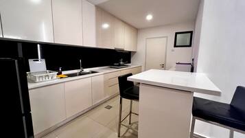 A modern kitchen with white cabinets, a black countertop, and a small bar area.