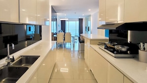 A modern kitchen with a central island, stainless steel appliances, and a dining area with a view. - Grand Ion Delemen by Manhattan Group (Genting Highlands)