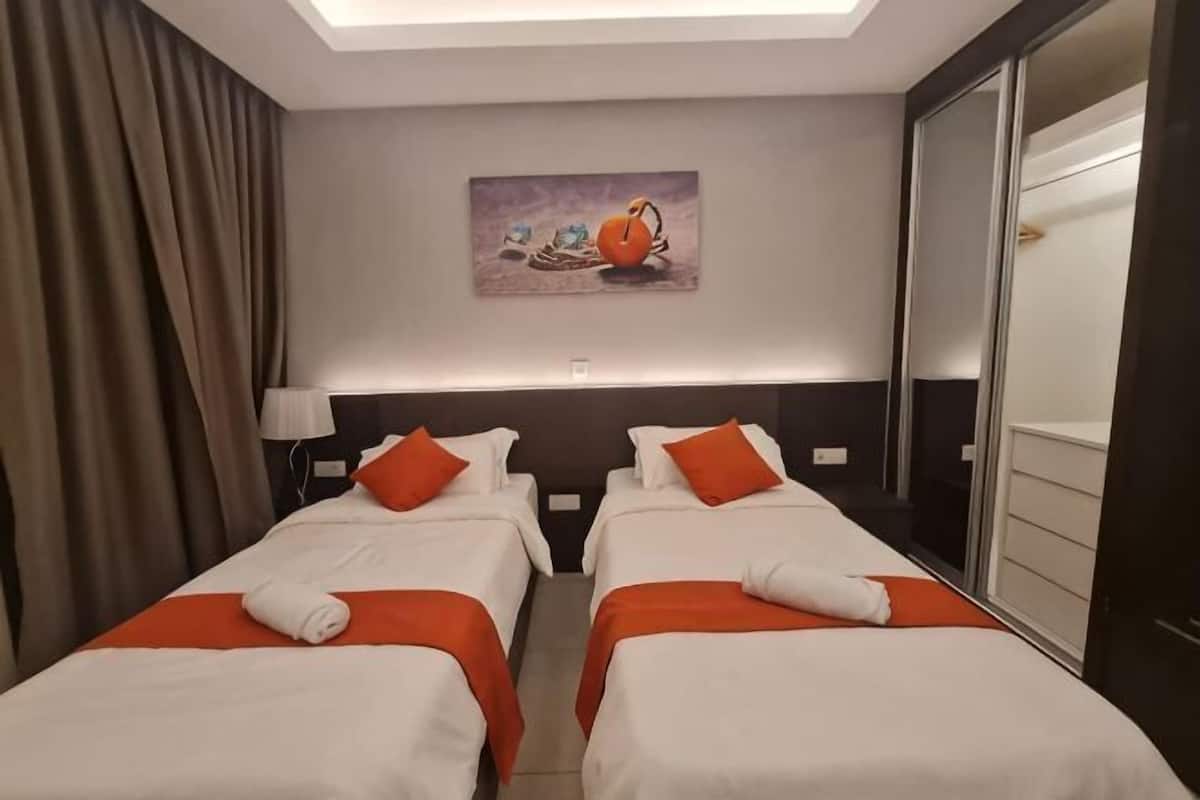 Habitación de hotel con dos camas, un cuadro en la pared y una puerta corredera.