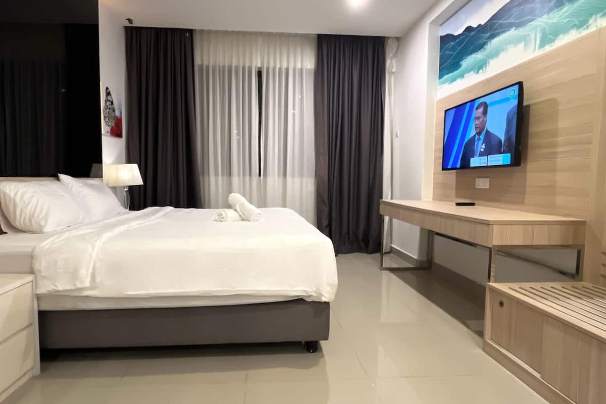 Una habitación de hotel con una cama, un escritorio, un televisor y un cuadro en la pared.