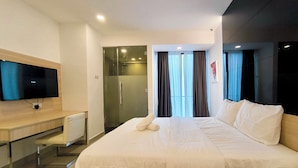 A hotel room with a large bed, a desk, a television, and a shower area. - Grand Ion Delemen by Manhattan Group (Genting Highlands)