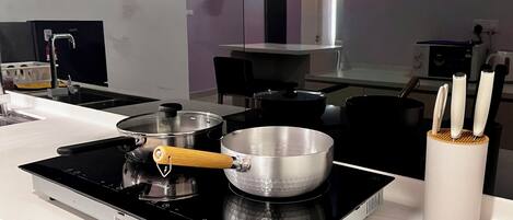 Una cocina con estufa, ollas y un soporte para cuchillos.