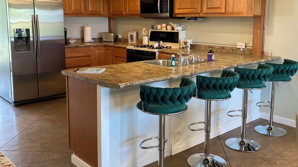 A modern kitchen with wooden cabinets, stainless steel appliances, and a central island with bar stools. - Stay at GLORIA’S GETAWAY, a tranquil pastoral setting minutes from everything! (Winamac)