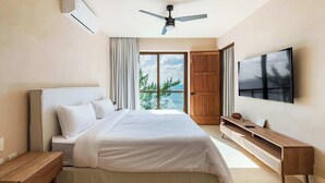 Un dormitorio con cama, televisión, ventilador de techo y vistas al exterior.
