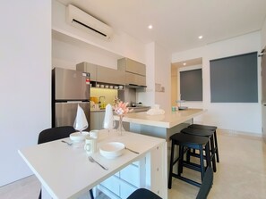 Modern kitchen with stainless steel appliances, oven, and microwave, plus a dining area with a simple table setting.