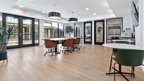 A modern conference room with a large table, chairs, and a potted plant.