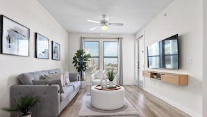 A modern living room with a grey sofa, a white coffee table, and a ceiling fan.