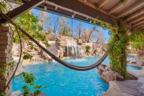 Eine Hängematte über einem Pool mit Wasserfall und felsiger Landschaft.