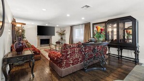A living room with a fireplace, a sofa, a table with a vase, and a cabinet.