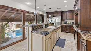 A kitchen with a large island, built-in appliances, and a view of a pool.