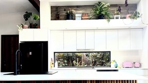 Una cuina moderna amb una illa gran, armaris blancs i un televisor integrat.