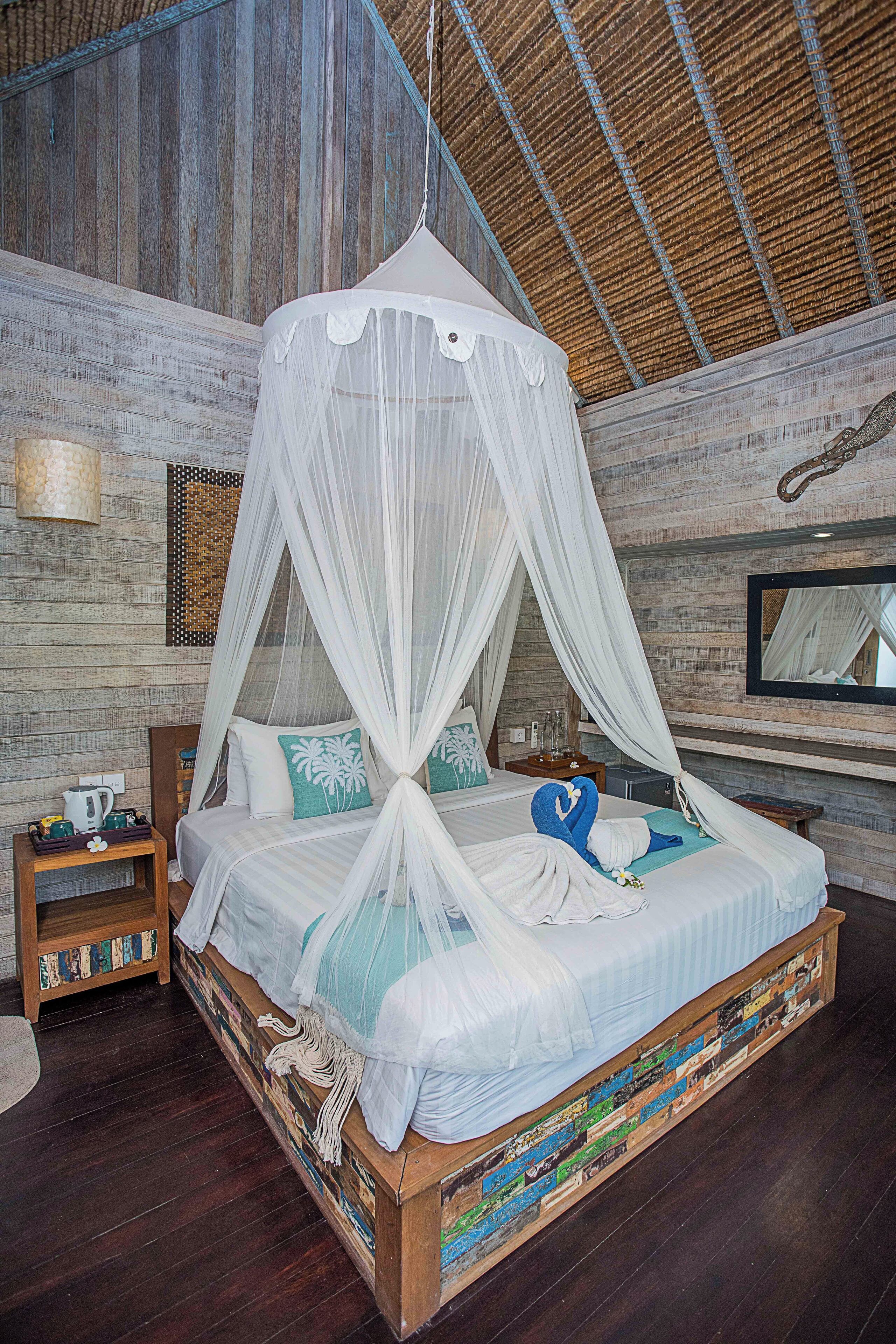 Een bed met hemelbed, houten hoofdbord en decoratieve kussens.