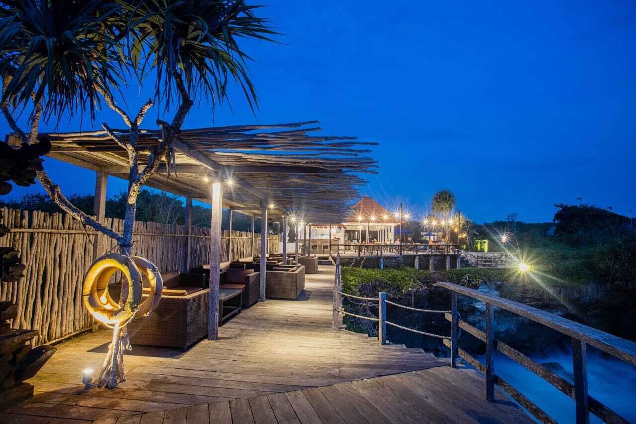 A wooden deck with outdoor seating, a covered area, and a view of a river.