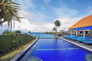 A swimming pool with blue tiles, lounge chairs, and a view of the ocean. - Water Blow Huts (Lembongan Island)