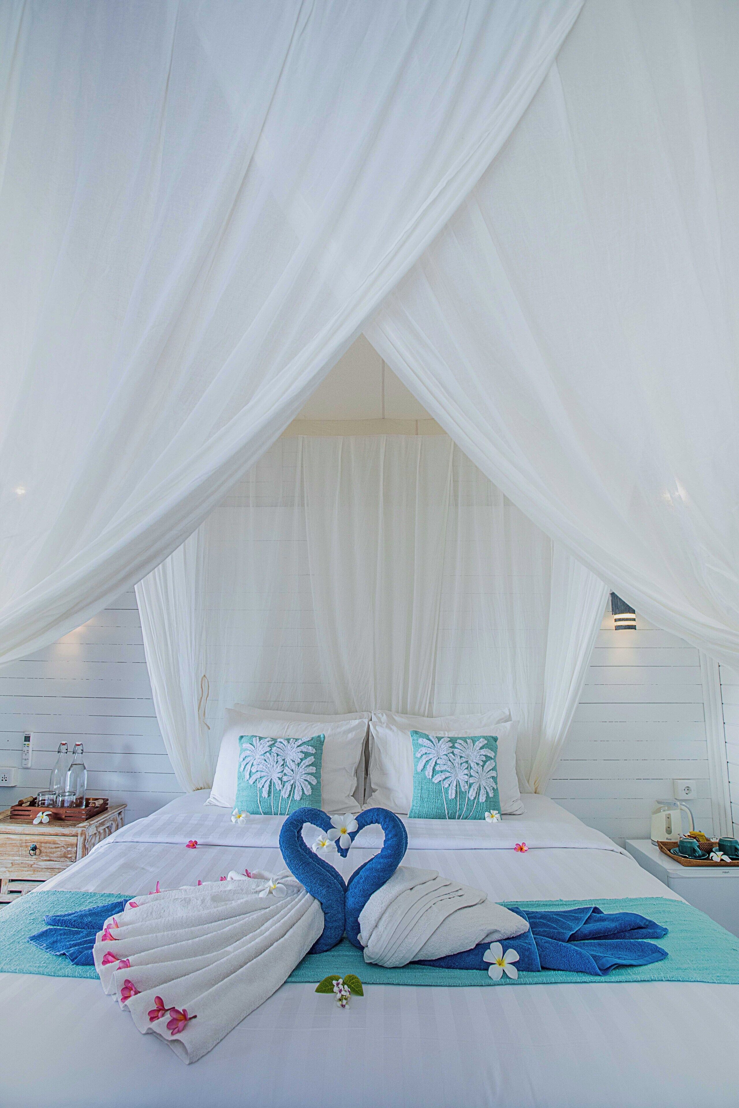 A bed with white linens, a canopy, and decorative pillows.