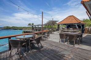 A wooden deck with outdoor seating, overlooking the ocean. - Water Blow Huts (Lembongan Island)