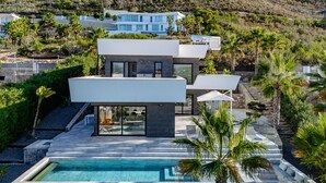 A modern two-story house with a swimming pool, surrounded by lush greenery and a hillside. - Vacation home Leda by Interhome (Jávea)