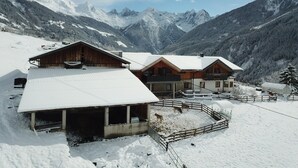 Een bergchalet bedekt met sneeuw, met houten hutten en een omheind erf.