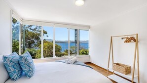 Un dormitorio con una cama grande, una hamaca de madera y vistas al mar.