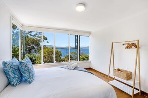 A bedroom with a large bed, a wooden swing, and a view of the sea. - Lemonade by the Beach: Serene Huon Valley Retreat with Water Views (Police Point)