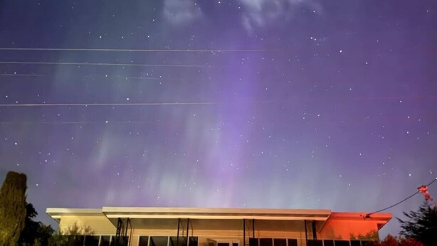 Un edificio moderno con techo plano y ventanas amplias, bajo un cielo estrellado.