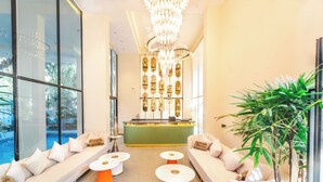 A modern reception area with a green counter, white sofas, and a large chandelier. - Vilmaris Luxury Hotel in Calangute (Calangute)