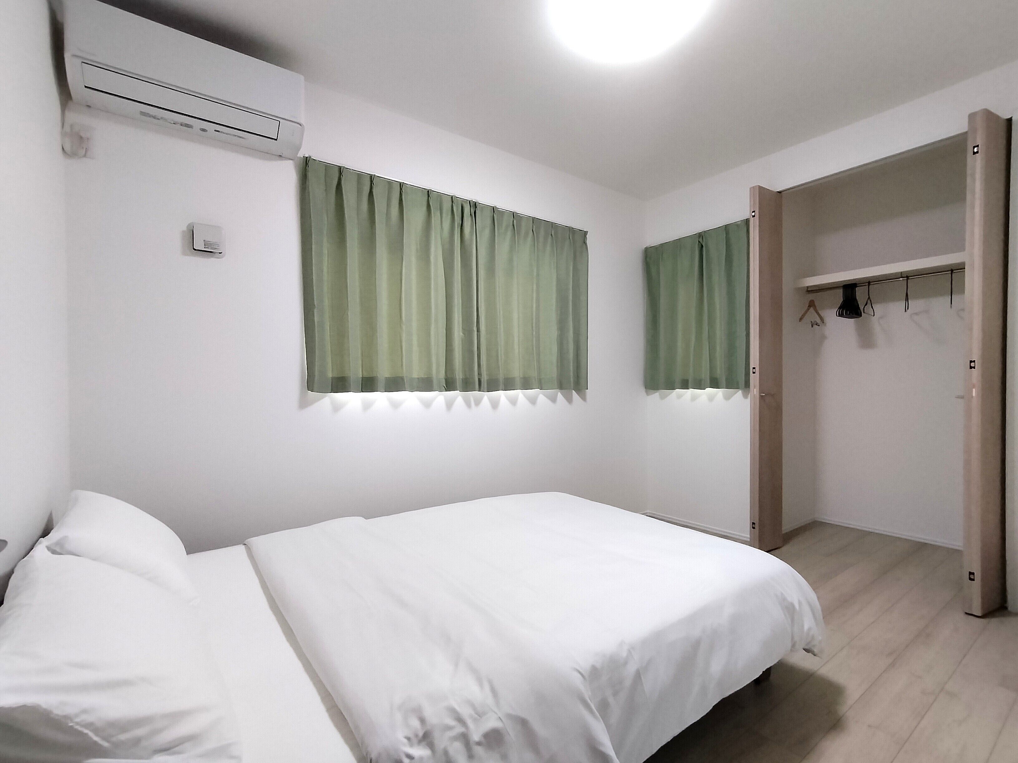 Um quarto com cama, guarda-roupa e janela com cortinas.