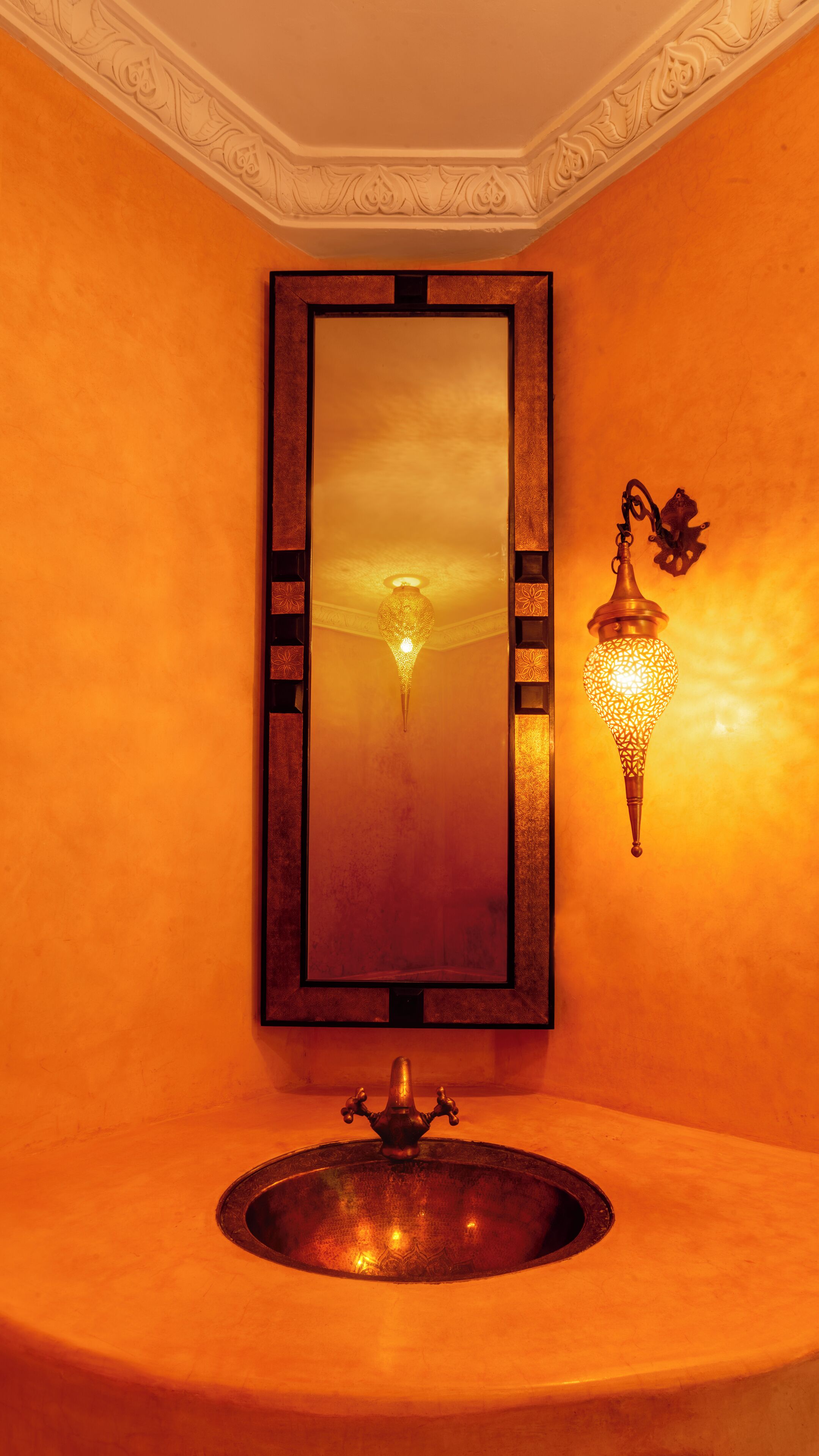 A bathroom with a large mirror, a round sink, and two wall-mounted lights.