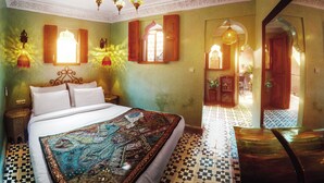 A traditional Moroccan-style bedroom with a bed, ornate wall lamps, and a chandelier. - Riad Roxanne (Marrakech)