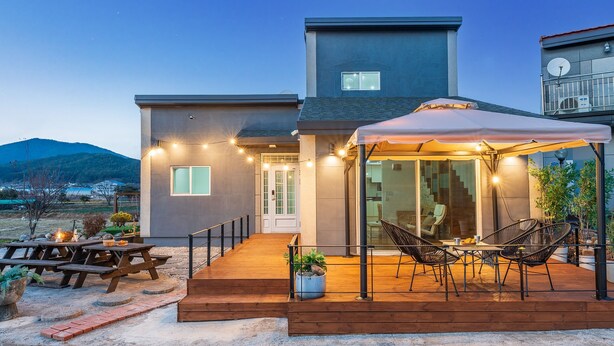 Une maison moderne dotée d’un patio couvert, d’un espace salon extérieur et offrant une vue sur les montagnes.