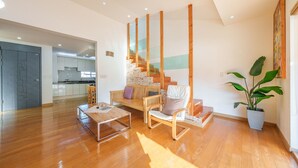 Un salon moderne avec un plancher en bois, une table basse en verre, un canapé et un escalier doté de rampes en verre.