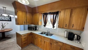 Una cocina con armarios de madera, un fregadero, un microondas y una cafetera.