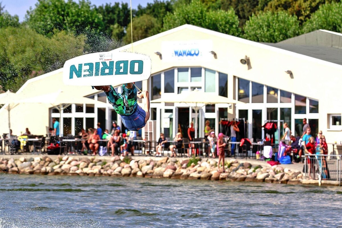 A person performing a trick on a wakeboard in front of a building with a sign that reads "DORIN".