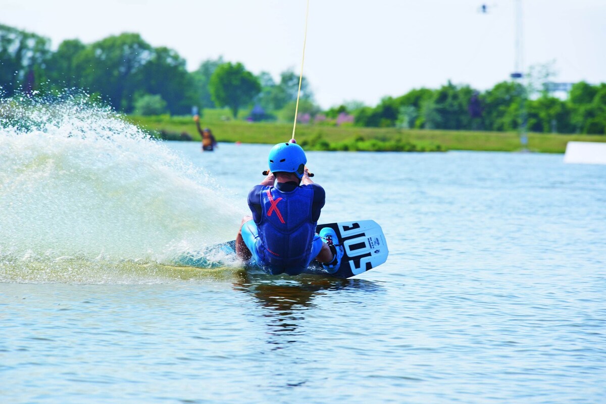 A wakeboarding activity on a lake with a person in blue gear.