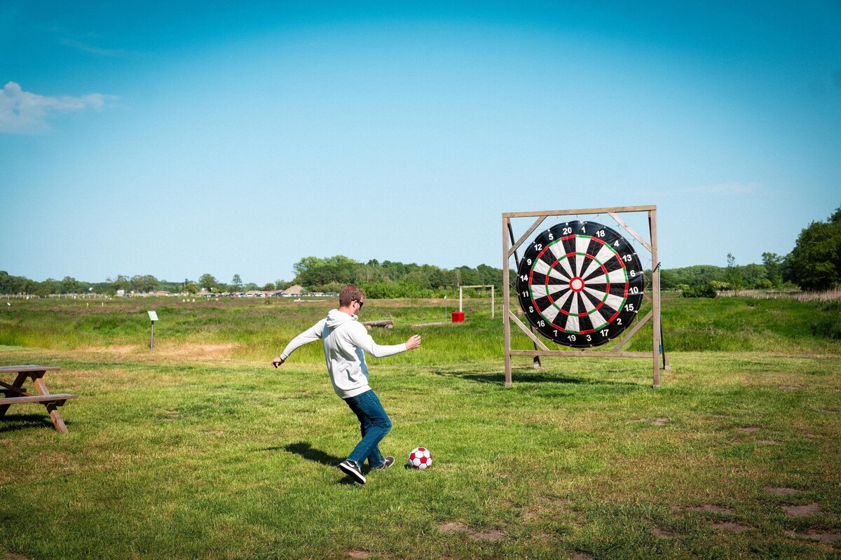 A person playing soccer in a grassy field with a dartboard in the background.