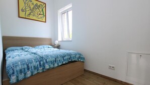 Ein Schlafzimmer mit einem hölzernen Bett, einem Fenster und einer Heizung.