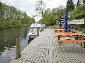 A wooden dock with a boat, picnic tables, and umbrellas.
