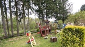 Un'area giochi con uno scivolo, strutture per arrampicata e una piccola casetta.
