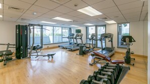 Ein Fitnessstudio mit Laufbändern, Kraftgeräten und Kurzhanteln.