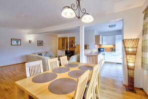 Una cocina moderna con armarios de madera, un comedor con mesa y sillas de madera, y un pasillo que conduce a una sala de estar.
