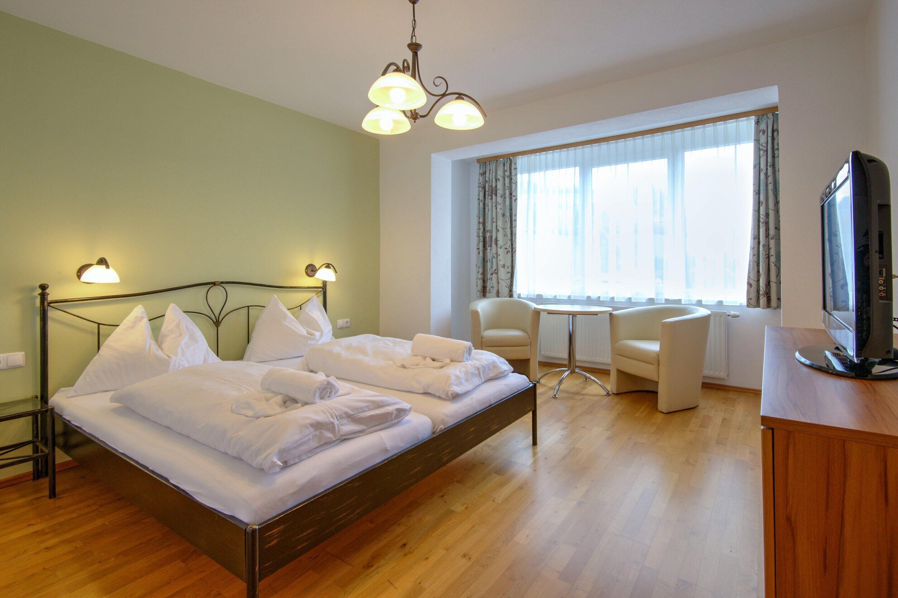 Een hotelkamer met een bed, een bureau, een stoel en een televisietoestel.