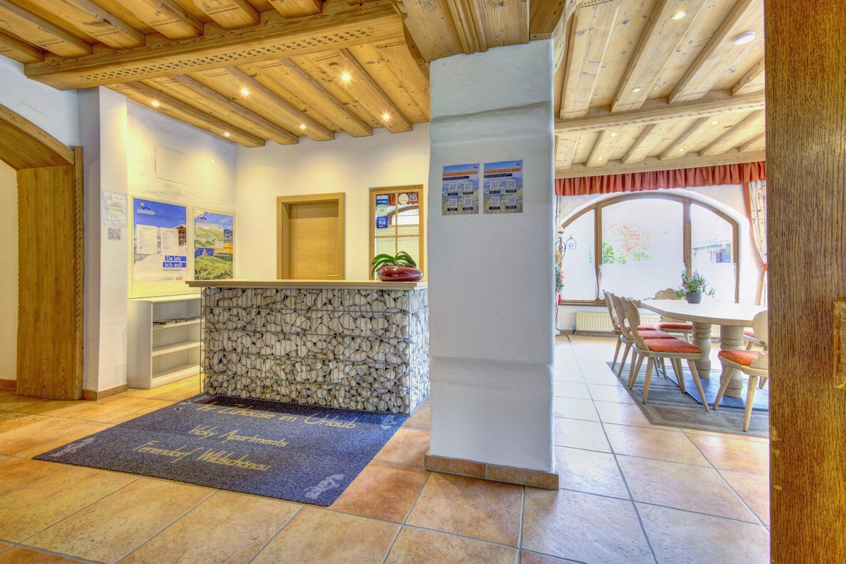 A reception area with a stone counter, a blue welcome mat, and a wooden ceiling.
