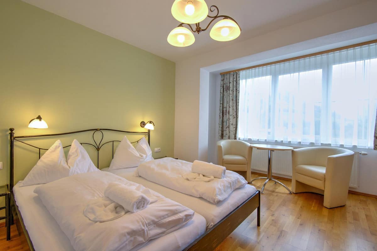 A hotel room with a bed, two bedside tables, a chair, and a large window with a view.
