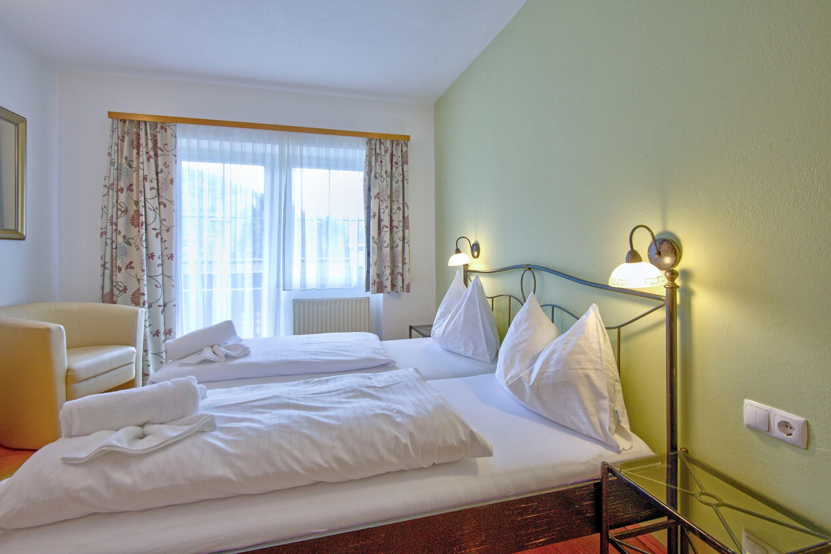 Een hotelkamer met een bed, twee kussens, een stoel en een lamp.