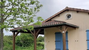 Een gebouw met een pannendak, een overdekte veranda en blauwe deuren.