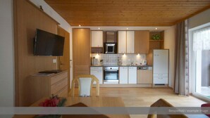 Eine moderne Küche mit Holzausstattung, einem eingebauten Backofen und einem flachbildfernseher, der über der Arbeitsfläche angebracht ist.