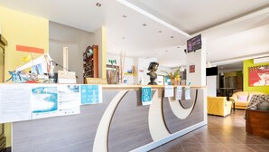 Un comptoir d’accueil avec une pancarte indiquant « RÉCEPTION », une sculpture en buste et divers affiches d’information.
