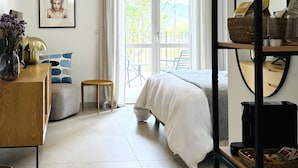 A bedroom with a bed, a desk with a lamp, a chair, a small table, and a window with curtains. - A Casa Guesthouse (Mombaruzzo)