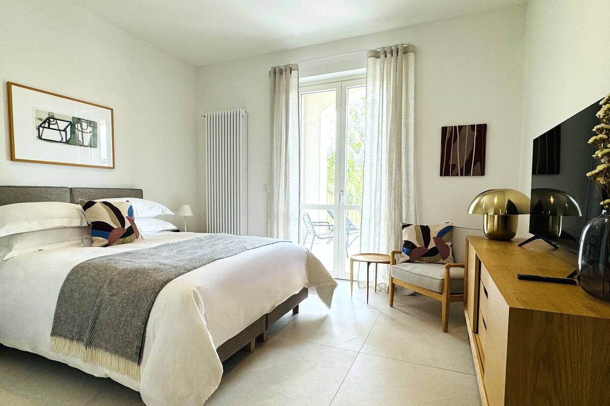 A modern bedroom with a bed, a desk, a chair, and a TV.