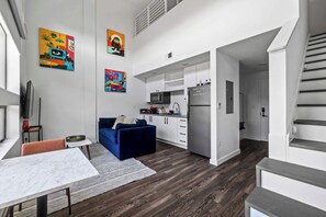 A modern apartment with a living area, kitchen, and staircase.